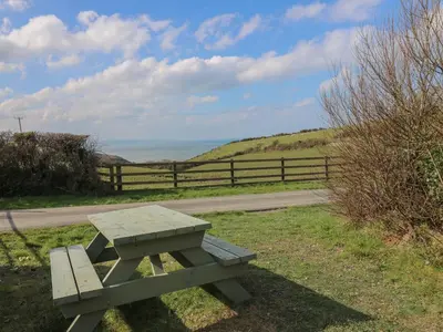 a picnic table sitting in the grass near a fence at Sea the Stars in New Quay