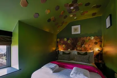 a bedroom with a large bed with a green wall at The Hive, Central Ludlow, Free Parking, Boutique Hotel Style in Ludlow