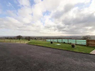 a road with a fence and a view of a field at Border View Lodge in Welshpool