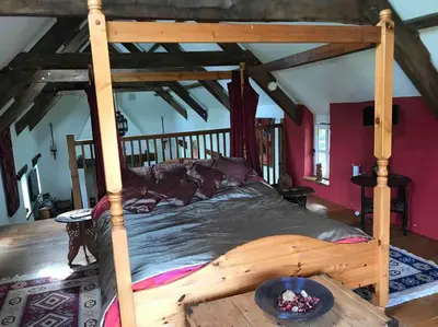 a bedroom with a wooden bed in a room at Ysgubor y Tanybryn The barn with a view and a spa. in Tregaron