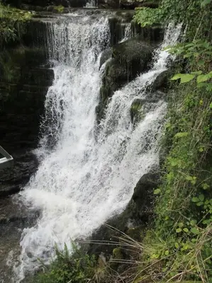 a waterfall on the side of a river at Ysgubor y Tanybryn The barn with a view and a spa. in Tregaron