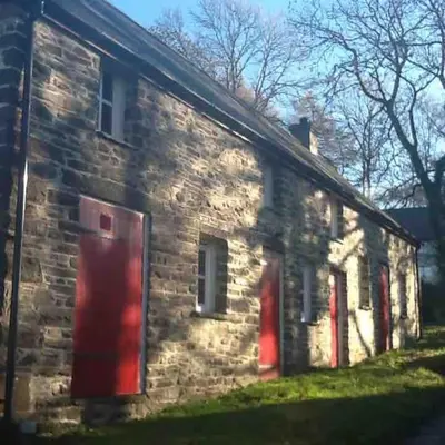 an old stone house with red doors and windows at Ysgubor y Tanybryn The barn with a view and a spa. in Tregaron
