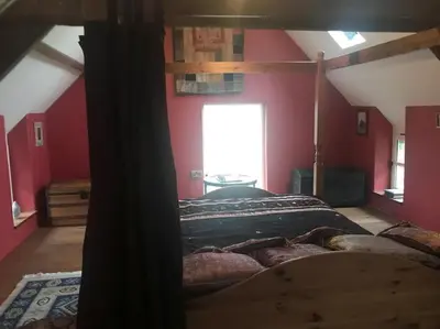 a bedroom with a bed in a room with red walls at Ysgubor y Tanybryn The barn with a view and a spa. in Tregaron