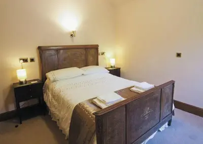 a bedroom with a large wooden bed with two night stands at Penbryn Mynach Holiday Cottage in Barmouth