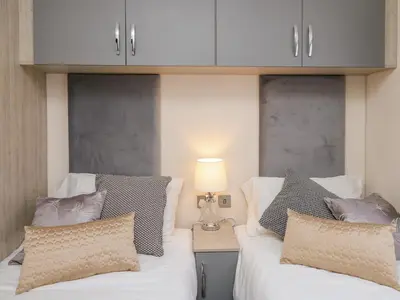 a bedroom with two beds and a table with a lamp at 43 The Deri in New Quay