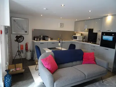 a living room with a couch and a kitchen at Ty Ni Holiday Apartment Aberdovey in Aberdyfi