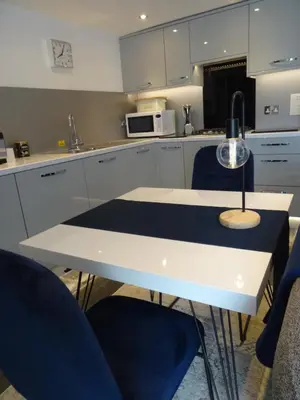 a kitchen with a white table and two blue chairs at Ty Ni Holiday Apartment Aberdovey in Aberdyfi