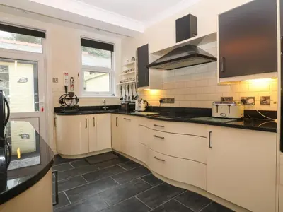 a kitchen with white cabinets and black counter tops at Morolwg in Barmouth