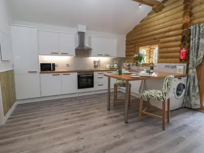 a kitchen with white cabinets and a wooden wall at Redwood Lodge in Ellesmere