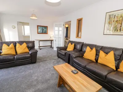 a living room with black leather couches and yellow pillows at Borthwen in Barmouth