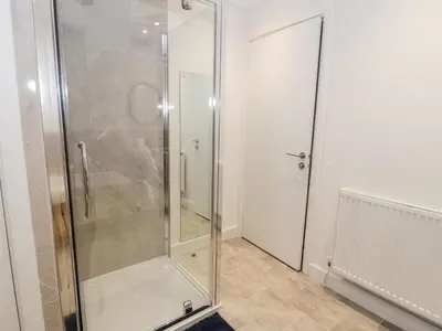 a shower with a glass door in a bathroom at Borthwen in Barmouth