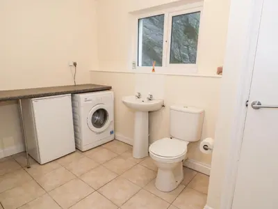 a bathroom with a toilet and a sink and a washing machine at Borthwen in Barmouth