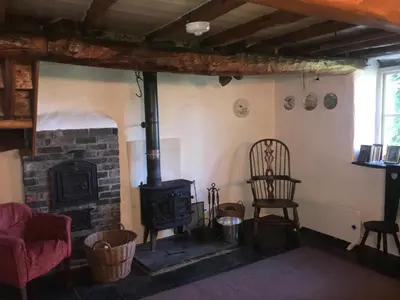 a living room with a wood stove and a chair at Tanybryn (Welsh meaning on the brow of a hill) in Tregaron