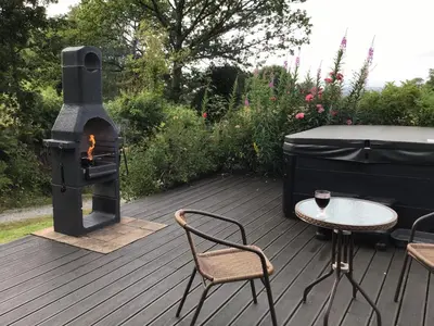 a wood fired grill and a table and chairs on a deck at Tanybryn (Welsh meaning on the brow of a hill) in Tregaron
