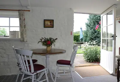 a table with two chairs and a table with flowers on it at Dee's Cottage at Brinsop in Hereford