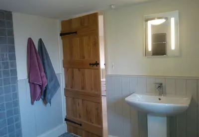 a bathroom with a sink and a wooden door at Dee's Cottage at Brinsop in Hereford