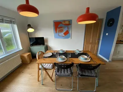a dining room with a wooden table and chairs at Bungalow, mountain and sea views parking in Aberdyfi