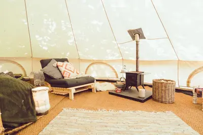 a room with a tent with a couch and a stove at Cuddfan Bach (The Little Hideaway) at Camp Plas in Welshpool