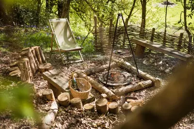 a fire pit and a chair next to a bench at Cuddfan Bach (The Little Hideaway) at Camp Plas in Welshpool