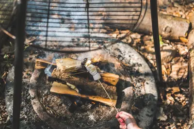 a person holding a stick around a grill at Cuddfan Bach (The Little Hideaway) at Camp Plas in Welshpool