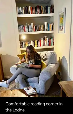 a woman sitting on a couch reading a book at Kookaburra lodge in Brecon