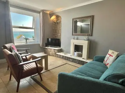 a living room with a blue couch and a fireplace at Min y Graig New Quay in New Quay