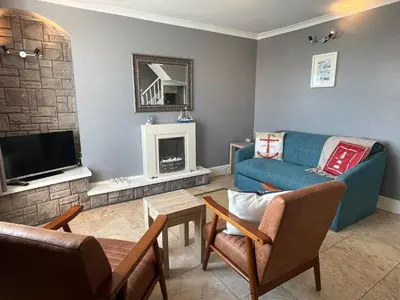 a living room with a blue couch and a fireplace at Min y Graig New Quay in New Quay