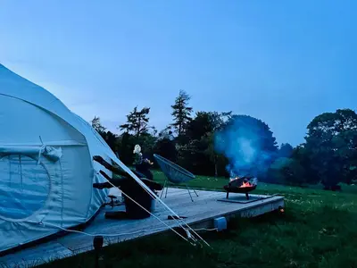 a tent and a grill with a fire in a field at Luxury Stargazing Glamping - Seren Aur with Hot Tub in Llanidloes
