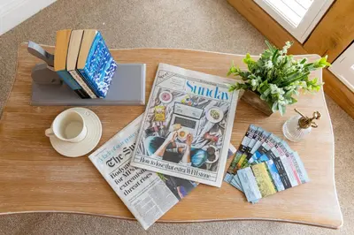 a coffee table with a newspaper and a magazine at Plas Robin in Montgomery