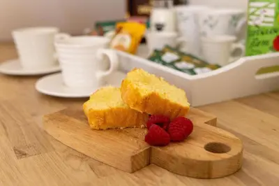 a piece of cornbread with raspberries on a cutting board at Plas Robin in Montgomery