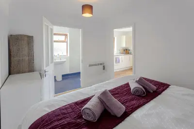 a white bedroom with two towels on a bed at Seabreeze Aberaeron in Aberaeron