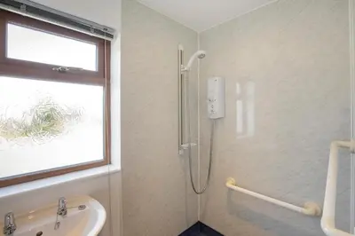 a shower in a bathroom with a sink and a window at Seabreeze Aberaeron in Aberaeron