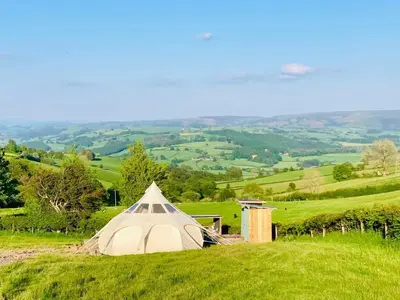 a tent on top of a green field at Luxury Stargazing Glamping - Seren Hardd with Hot Tub in Llanidloes