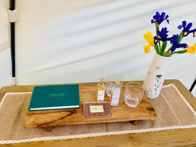 a table with a laptop and a vase with flowers at Luxury Stargazing Glamping - Seren Hardd with Hot Tub in Llanidloes