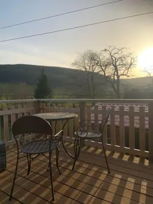two chairs and a table on a deck at Beautiful converted Coach house for two in Hoptonheath