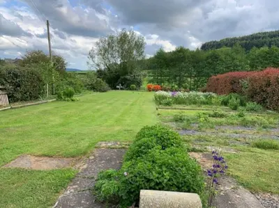 a garden with a field of grass and flowers at Beautiful converted Coach house for two in Hoptonheath
