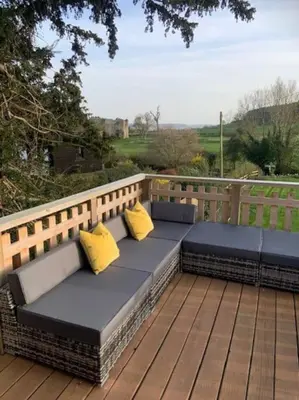 a bench with two yellow pillows sitting on a deck at Beautiful converted Coach house for two in Hoptonheath