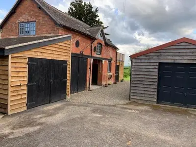 a garage with two doors and a brick building at Beautiful converted Coach house for two in Hoptonheath