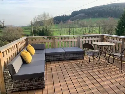 a patio with a bench and a table on a deck at Beautiful converted Coach house for two in Hoptonheath