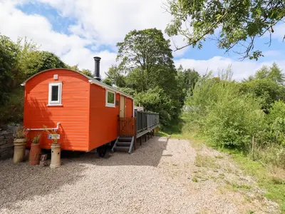 an orange tiny house sitting on top of a gravel road at Red Kite at Wild Valley Huts in Oswestry