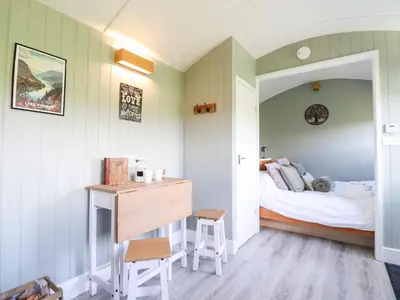 a bedroom with a bed and a desk with a desk at Cuckoo at Wild Valley Huts in Oswestry