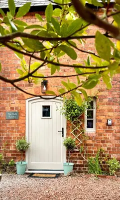a white door on a brick building with potted plants at The Old Rectory Tack Rooms in Shrewsbury