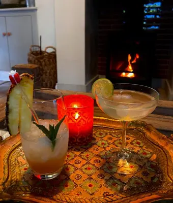 two cocktails sitting on a table with a fireplace at The Old Rectory Tack Rooms in Shrewsbury