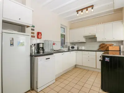 a kitchen with white cabinets and a refrigerator at Tawelfan in Llwyngwril