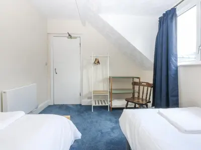 a bedroom with two beds and a chair and a window at Tawelfan in Llwyngwril