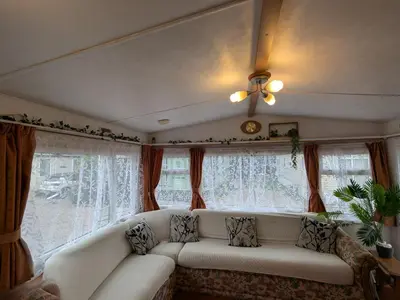 a living room with a white couch in front of windows at The fox den in Rhos-gôch