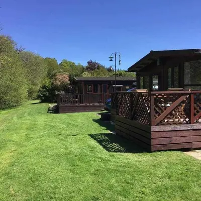 a house with a deck and a grass yard at Turtle Lodges 29 - Riverside in Builth Wells