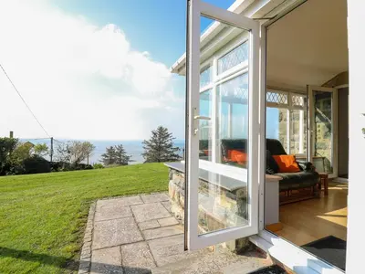 a sliding glass door to a patio with a view of the ocean at Mynydd ar Mor in Barmouth