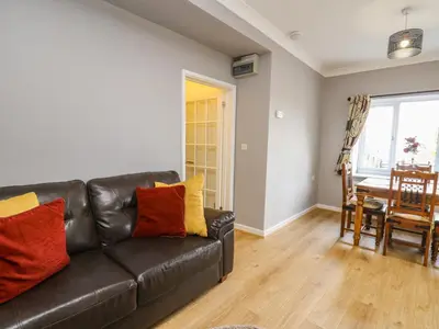 a living room with a black leather couch and a table at Mynydd ar Mor in Barmouth
