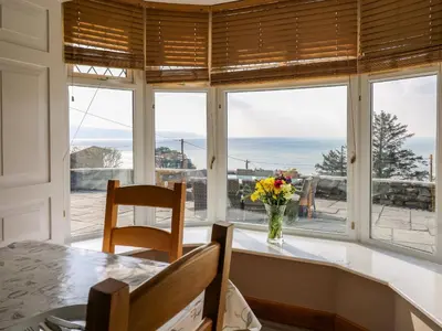 a dining room with a window with a vase of flowers at Mynydd ar Mor in Barmouth
